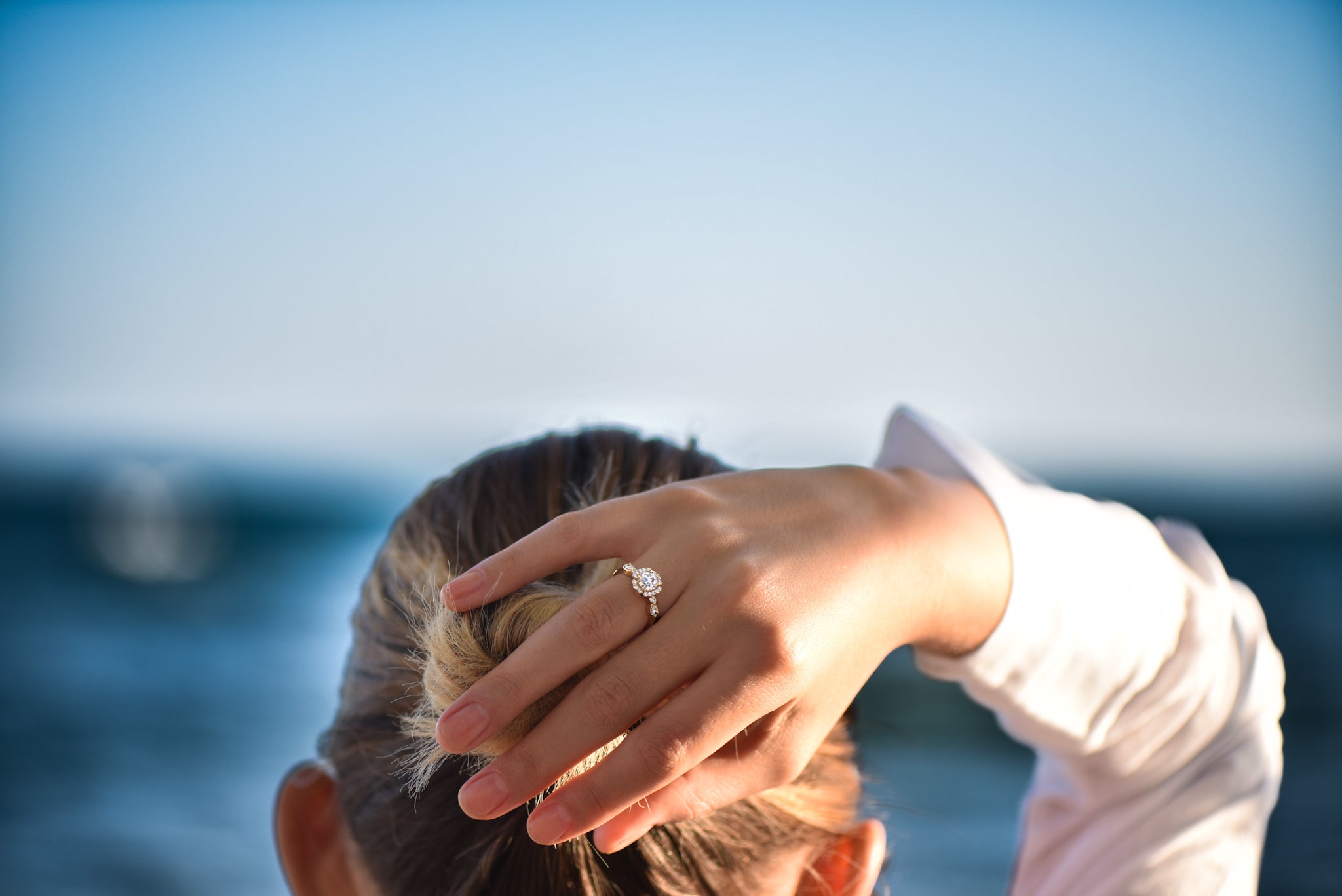 Woman gazing at the sea, wearing an engagement ring – a moment of calm, love, and promise.